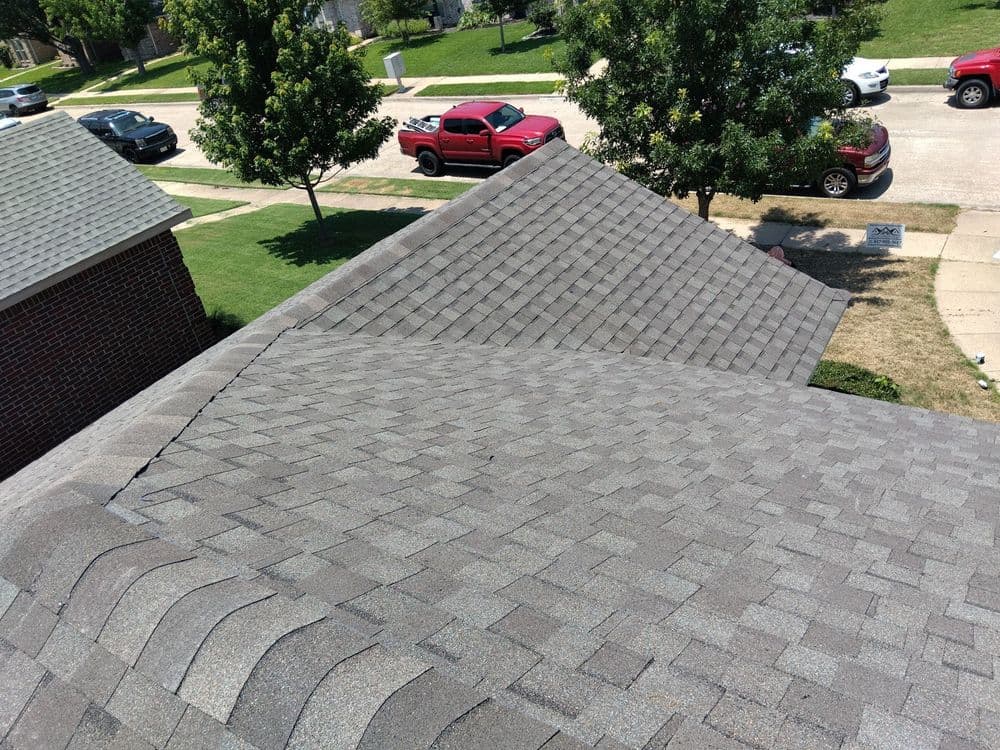 Aerial view of a residential roof with gray shingles and neighboring houses.