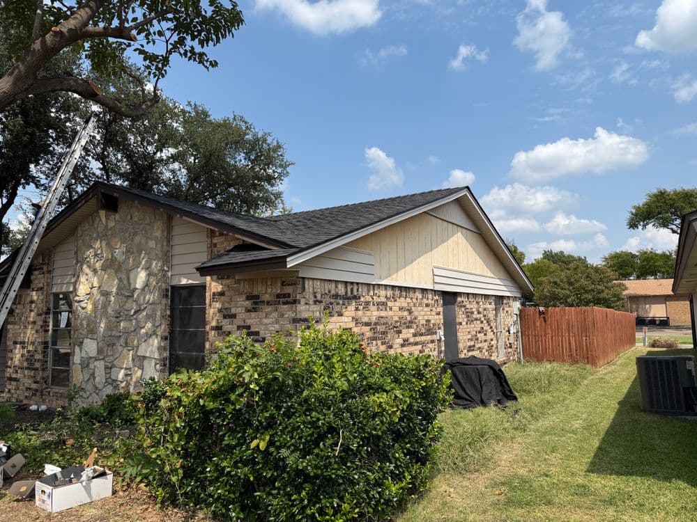 Home exterior with stone and wood siding, green lawn, and wooden fence under a blue sky.